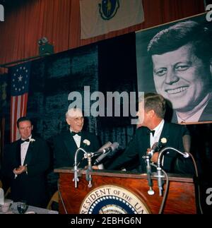 Reise nach Maine u0026 Massachusetts: Boston, Fundraising Dinner im Commonwealth Armory, 8:13pm Uhr. Präsident John F. Kennedy hält Bemerkungen während des u201cAll New England Salute Dinneru201d zu seinen Ehren im Commonwealth Armory in Boston, Massachusetts. Der Sprecher des Repräsentantenhauses, John W. McCormack (Massachusetts), steht in der Mitte; der Co-Vorsitzende des Abendessens, Thomas J. White, steht ganz links. Stockfoto