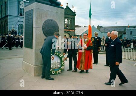 Reise nach Europa: Irland, Wexford: Ankunft, Begrüßung Oberbürgermeister Thomas Byrne, Kranzniederlegung am John Barry Memorial, Ansprache am Redmond Place. 1:10PM UHR. Präsident John F. Kennedy (links, unterstützt von einem nicht identifizierten Mann) legt einen Kranz an der Basis des Commodore John Barry (USN) Memorial am Crescent Quay in Wexford, Irland. Auf der rechten Seite sind (L-R): Oberbürgermeister von Wexford, Ratsmitglied Thomas F. Byrne; Naval Aide an den Präsidenten, Kapitän Tazewell T. Shepard, Jr.; Minister für auswärtige Angelegenheiten von Irland, Frank Aiken; und US-Botschafter in Irland, Matthew H. McCloskey. Stockfoto