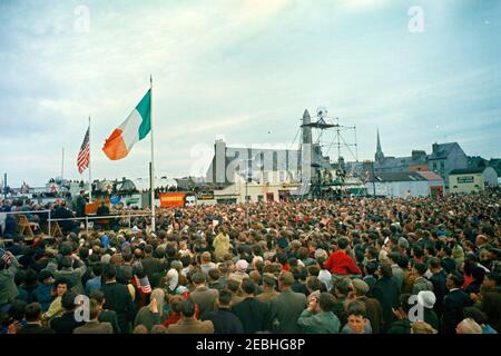 Reise nach Europa: Irland, Wexford: Ankunft, Begrüßung Oberbürgermeister Thomas Byrne, Kranzniederlegung am John Barry Memorial, Ansprache am Redmond Place. 1:10PM UHR. Präsident John F. Kennedy (links, am Rednerpult) hält eine Ansprache vor der Menschenmenge, die sich am Redmond Place in Wexford, Irland, während einer Begrüßungszeremonie zu seinen Ehren versammelt. Stockfoto