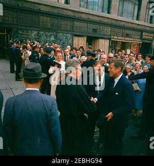 Reise nach Maine u0026 Massachusetts: Boston, Präsident Kennedy nimmt an der Messe in der St. Francis Xavier Church Teil, 10:02am Uhr. Präsident John F. Kennedy schüttelt sich bei seiner Abreise aus der St. Francis Xavier Chapel in Boston, Massachusetts, nach der Teilnahme an der Messe die Hände eines unbekannten Priesters. Eine große Menge beobachtet. Stockfoto