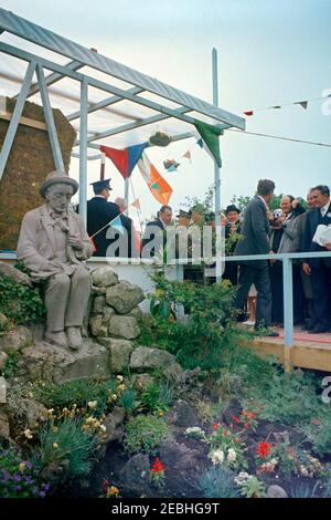 Europareise: Irland, Galway: Präsident Kennedy am Eyre Square, Bemerkungen und Abreise, 11:55am Uhr. Präsident John F. Kennedy (rechts, weggewandt) verlässt den Eyre Square in Galway, Irland, nach einer Begrüßungszeremonie zu seinen Ehren; Taoiseach (Premierminister) von Irland, Sean Lemass (Mitte), steht hinter Präsident Kennedy; alle anderen sind nicht identifiziert. Eine Statue des irischen Autors, Pu00e1draic u00d3 Conaire (von Albert Power modelliert), ist links. Stockfoto