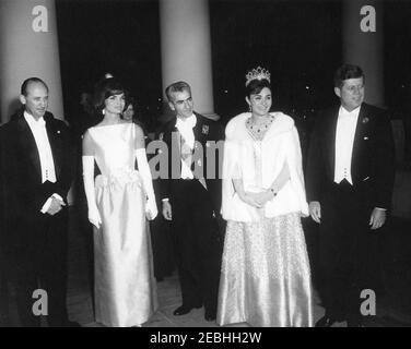 Abendessen zu Ehren des Schahs des Iran, Mohammad Reza Shah Pahlavi, 8:00pm Uhr. Mohammad Reza Pahlavi, die Shahanshah des Iran, und seine Frau, die Kaiserin Farah Pahlavi, kommen zu ihren Ehren zum Abendessen im Weißen Haus an. (L-R) Protokollchef Angier Biddle Duke, First Lady Jacqueline Kennedy, die Shahanshah, die Kaiserin und Präsident John F. Kennedy. North Portico, White House, Washington, D.C. Stockfoto