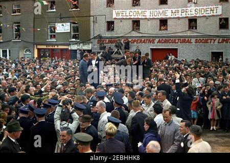 Europareise: Irland, New Ross. Präsident John F. Kennedy (Mitte links) begrüßt die Menschenmassen, die am New Ross Quay in New Ross, County Wexford, Irland, während einer Begrüßungszeremonie zu seinen Ehren versammelt sind. Auch abgebildet (hinter Präsident Kennedy zu Fuß): White House Secret Service Agent Gerald u201cJerryu201d Behn und Vorsitzender des New Ross Urban District Council, Andrew Minihan; der Präsident gab eine Adresse an dem Kai, von dem sein Urgroßvater, Patrick Kennedy, in die Vereinigten Staaten emigrierte. Stockfoto