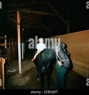 Caroline Kennedy (CBK) u0026 John F. Kennedy, Jr. (JFK, Jr.), in Fort Myer Stables. John F. Kennedy, Jr., sitzt auf einem Pferd während eines Besuchs in Fort Myer Stables in Arlington, Virginia. Stockfoto