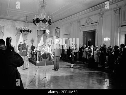 Staatsfuneral von Präsident Kennedy: In Ruhe im Ostraum des Weißen Hauses liegend. Der verstorbene Präsident John F. Kennedy liegt in Ruhe im Ostraum des Weißen Hauses; Präsident Kennedyu2019s mit Flagge drapierte Schatulle sitzt in der Mitte links. Stellvertretender Pressesprecher, Malcolm Kilduff, geht im Zentrum. Mitglieder der Ehrenwache stehen Wache; Mitglieder der Presse beobachten. Washington, D.C. Stockfoto