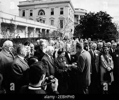 Besuch der Delegierten der Sitzung 1963, Verwaltungsrat des Beratenden Ausschusses für Poststudien, Universelle Postunion, 9:35am Uhr. Präsident John F. Kennedy (Mitte rechts) erhält ein Briefmarkenalbum bei einem Besuch internationaler Delegierter auf der Universellen Post-Unionu0027s 1963-Sitzung des Verwaltungsrats des Beratenden Ausschusses für Poststudien. Rose Garden, White House, Washington, D.C. Stockfoto