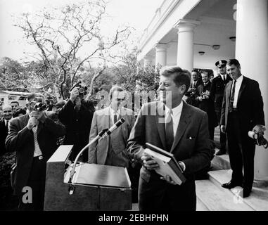 Besuch der Delegierten der Sitzung 1963, Verwaltungsrat des Beratenden Ausschusses für Poststudien, Universelle Postunion, 9:35am Uhr. Präsident John F. Kennedy (Mitte rechts) steht am Rednerpult, nachdem er den internationalen Delegierten auf der Universellen Post-Unionu0027s 1963-Sitzung des Verwaltungsrats des Beratenden Ausschusses für Poststudien Rede gehalten hat; Präsident Kennedy hält Briefmarkenalben, die ihm von den Delegierten präsentiert wurden. Stellvertretender Generalpostmeister für das Büro für Transport und internationale Dienstleistungen und Vorsitzender des Direktoriums Councilu0027s Ausschuss, WI Stockfoto