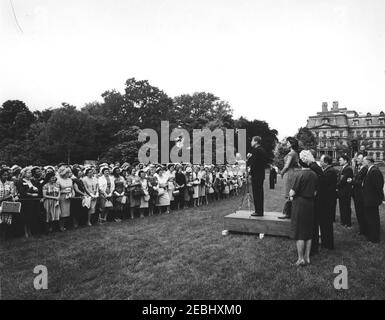 Besuch der Teilnehmer der Wahlkampfkonferenz für Demokratische Frauen 1962, 9:35am Uhr. Präsident John F. Kennedy (auf der Plattform) hält Bemerkungen an die Teilnehmer der Wahlkampfkonferenz 1962 für demokratische Frauen; First Lady Jacqueline Kennedy steht auf der Plattform mit Präsident Kennedy. Ebenfalls abgebildet (rechts): Vizepräsidentin des Demokratischen Nationalkomitees (DNC), Margaret B. Price; Vizepräsident Lyndon B. Johnson (meist versteckt); Senator Hubert H. Humphrey (Minnesota); Repräsentant Hale Boggs (Louisiana); Senator George Smathers (Florida); Senator Mike Mansfield (Montana); Vorsitzender von t Stockfoto