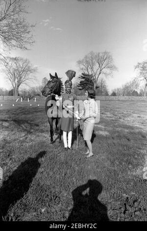 First Lady Jacqueline Kennedy (JBK) und Caroline Kennedy (CBK) erhalten u0022Sardar,u201d ein Pferd, das vom pakistanischen Präsidenten Ayub Khan in Fort Myer Stables, Arlington, Virginia, geschenkt wurde. First Lady Jacqueline Kennedy besucht mit ihrem Pferd, u0022Sardar,u0022 als Geschenk des pakistanischen Präsidenten Mohammad Ayub Khan, während ihrer Reise nach Pakistan. Ein nicht identifizierter pakistanischer Militäroffizier steht im Zentrum. Fort Myer Stables, Arlington, Virginia. Stockfoto