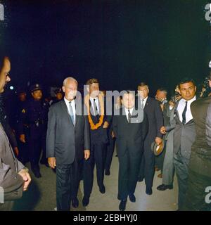 Reise in die westlichen Staaten: Honolulu, Hawaii, Ankunft am Honolulu International Airport, 9:10pm Uhr. Präsident John F. Kennedy (Mitte, trägt eine Blume lei) geht mit Regierungsbeamten nach seiner Ankunft am Honolulu International Airport in Honolulu, Hawaii. Gouverneur von Hawaii, John A. Burns, steht links von Präsident Kennedy; Senator Daniel Inouye (Hawaii) steht rechts vom Präsidenten. Ebenfalls im Bild: Vertreter Spark M. Matsunaga (Hawaii); Geheimagenten des Weißen Hauses, Gerald A. u0022Jerryu0022 Behn und Tony Sherman. [Anmerkungen: Flecken entlang der linken und rechten Ränder sind dem Original Stockfoto