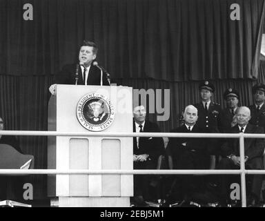 Dedication Ceremonies, Dulles International Airport, 11:12am Uhr. Präsident John F. Kennedy (auf dem Rednerpult) hält Bemerkungen bei der Einweihungszeremonie für den internationalen Flughafen Dulles, benannt nach dem verstorbenen Staatssekretär John Foster Dulles. Auf speakersu2019 Plattform rechts: Administrator der Federal Aviation Agency (FAA), Najeeb Halaby; Gouverneur von Virginia, Albertis S. Harrison, Jr.; Stabschef der United States Air Force, General Curtis E. LeMay; Militärhilfe für den Präsidenten, General Chester V. Clifton; ehemaliger Präsident, General Dwight D. Eisenhower; Direktor des Central Int Stockfoto