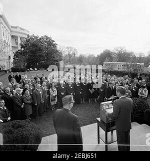 Besuch der Delegierten der Sitzung 1963, Verwaltungsrat des Beratenden Ausschusses für Poststudien, Universelle Postunion, 9:35am Uhr. Präsident John F. Kennedy (rechts, an einem Rednerpult) hält an die internationalen Delegierten der Universellen Post Unionu0027s 1963-Sitzung des Verwaltungsrats des Beratenden Ausschusses für Poststudien Bemerkungen. Die stellvertretende Generalpostmeisterin Sidney W. Bishop steht links von Präsident Kennedy; eine nicht identifizierte Stenographin und Korrespondentin des Weißen Hauses für United Press International (UPI), Helen Thomas, steht rechts. Rose Garden, White House, Washington, D Stockfoto