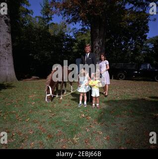 Präsident Kennedy, First Lady Jacqueline Kennedy (JBK), Caroline Kennedy (CBK) u0026 John F. Kennedy, Jr. (JFK, Jr.), mit Pony u201cLeprechaunu201d, Geschenk des irischen Präsidenten u00c9amon de Valera. Präsident John F. Kennedy, First Lady Jacqueline Kennedy und ihre Kinder, Caroline Kennedy und John F. Kennedy, Jr., stehen mit einem Connemara Pony, Leprechaun, als Geschenk des Präsidenten von Irland, u00c9amon de Valera. South Lawn, White House, Washington, D.C. Stockfoto