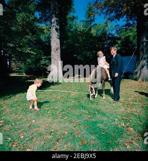 Präsident Kennedy, First Lady Jacqueline Kennedy (JBK), Caroline Kennedy (CBK) u0026 John F. Kennedy, Jr. (JFK, Jr.), mit Pony u201cLeprechaunu201d, Geschenk des irischen Präsidenten u00c9amon de Valera. Präsident John F. Kennedy besucht mit seinen Kindern Caroline Kennedy und John F. Kennedy, Jr.; Caroline sitzt auf einem Connemara Pony, Leprechaun, als Geschenk des Präsidenten von Irland, u00c9amon de Valera. South Lawn, White House, Washington, D.C. Stockfoto