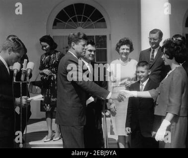 Präsentation der Young American Medals an Gerald L. Davis (Oregon), Gordon B. Kilmer (Michigan) und Mary Ann Kingry (Michigan), 10:15am Uhr. Präsident John F. Kennedy nimmt an der Verleihung der Young American Medals for Tapfery and Service Teil. Präsident Kennedy schüttelt sich die Hände mit der Medaillengewinnerin Mary Ann Kingry aus Saginaw, Michigan. Von links nach rechts: Generalstaatsanwalt Robert F. Kennedy (an Mikrofonen); nicht identifiziert (hinten); der Präsident; Vertreter Al Ullman (Oregon); Senatorin Maurine Neuberger (Oregon); Medaillenempfänger Gerald Lee Davis aus Ontario, Oregon; Vertreter Jame Stockfoto