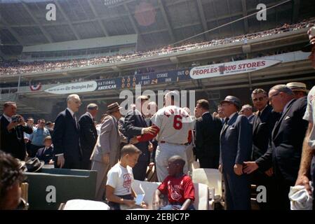 1962 All Star Baseball Spiel im D.C. Stadium, 12:52pm Uhr. Präsident John F. Kennedy begrüßt Outfielder für die National League, Stan Musial (St. Louis Cardinals), während der 32nd Major League Baseball (MLB) All-Star Game. Im Vordergrund stehend (L-R): Nicht identifizierter Mann mit Kamera; Sprecher des Repräsentantenhauses, John W. McCormack (Massachusetts); Vizepräsident Lyndon B. Johnson (weggewandt); Sonderassistent des Präsidenten, Dave Powers; Senator Hubert H. Humphrey von Minnesota (hinten, meist versteckt); Präsident Kennedy; Senator Stuart Symington von Missouri (hinten, teilweise versteckt); Stockfoto