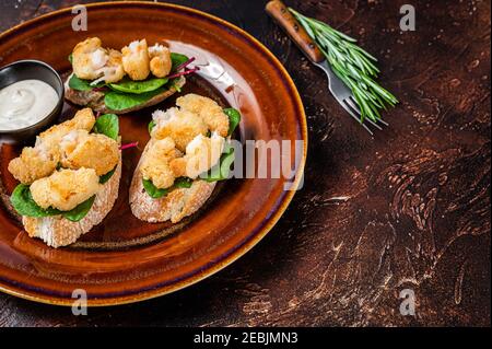 Sandwiches mit gebratenen Garnelen, Garnelen, Spinat und Mangold-Salat auf einem rustikalen Teller. Dunkler Hintergrund. Draufsicht. Speicherplatz kopieren Stockfoto