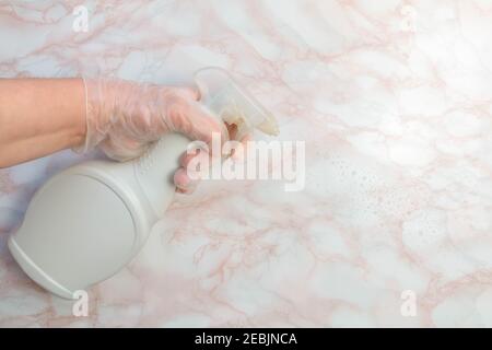 Hand in Handschuh mit Desinfektionsflüssigkeit in der Flasche zum Töten von Coronavirus. Oberfläche mit Desinfektionsflüssigkeit besprüht, um berührende Oberflächen zu reinigen. Coronavir Stockfoto