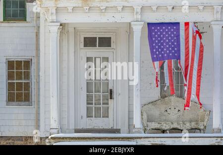 Zerfetzte amerikanische Flagge, die senkrecht auf der Veranda hing Ein altes Haus Stockfoto