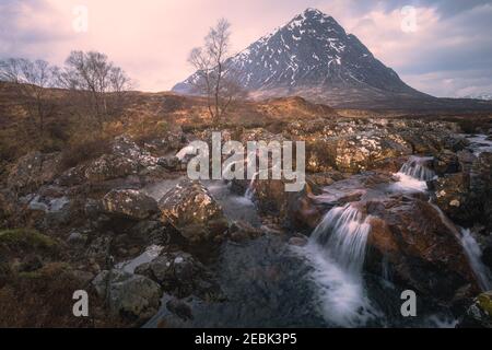 Moody, dramatische Landschaft des berühmten Buachaille Etiv Mor und River Coupall Wasserfall in Glencoe in den schottischen Highlands. Stockfoto