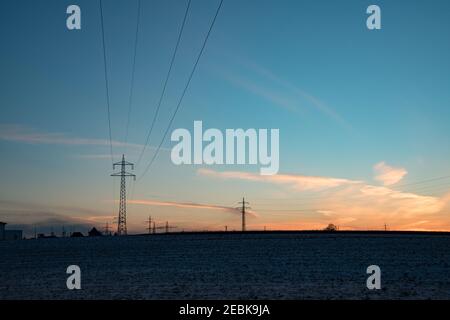 Elektrische Masten silhouetted in der Abenddämmerung, als sie elektrische Energie über das Land transportieren. Sie transportieren Strom. Stockfoto