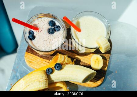 Zwei Gläser Banane Blaubeer Milchshake oder Smoothie mit Trinken Stroh und Banane Stockfoto