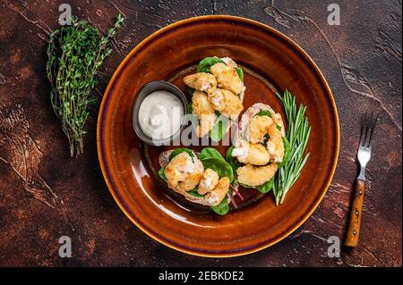 Sandwiches mit gebratenen Garnelen, Garnelen, Spinat und Mangold-Salat auf einem rustikalen Teller. Dunkler Hintergrund. Draufsicht Stockfoto