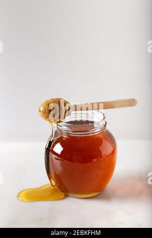 Honigstock mit fließendem Honig und Bienenpollengranulat auf dem Marmorhintergrund. Stockfoto