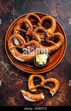 Frisch gebackene hausgemachte Brezel mit Salz auf einem rustikalen Teller. Dunkler Hintergrund. Draufsicht Stockfoto