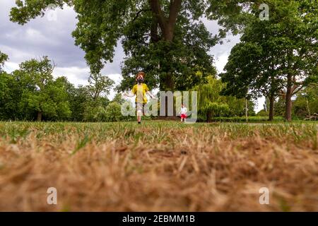 Zwei Kinder laufen im Park an einem sonnigen Sommer Tag Stockfoto