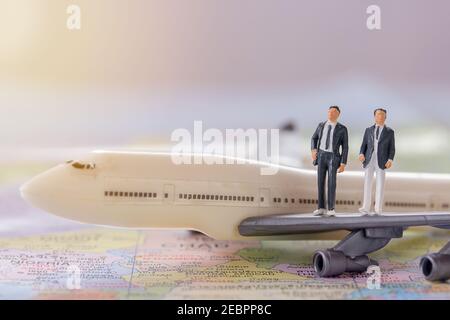 Miniatur Menschen - Figur Geschäftsleute auf weißem Flugzeug Modell mit verschwommenem Hintergrund stehen. Business Finance und Reisekonzept. Stockfoto