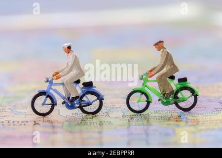Miniatur Menschen - Figur Geschäftsmänner Radfahren auf der Weltkarte mit verschwommenem weißen Flugzeug Hintergrund. Business Finance und Reisekonzept. Stockfoto