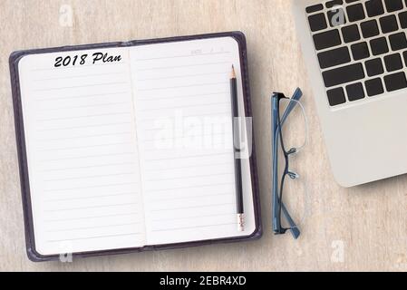 Konzeptgeschäft von Notebook, Laptop-Computer, schwarzen Bleistift und Brille auf einem alten Holztisch Hintergrund. Öffnen Tagebuch und Bleistift mit 2018 Plan Wörter. Stockfoto