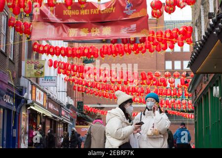 London, Großbritannien. Februar 2021, 12th. Ein Paar mit Gesichtsmasken als Vorsichtsmaßnahme gegen die Ausbreitung von covid-19 geht entlang Gerrard Street während des chinesischen Neujahrs.die Feierlichkeiten des chinesischen Neujahrs 2021 beginnt mit dem Neumond in London. Kredit: SOPA Images Limited/Alamy Live Nachrichten Stockfoto