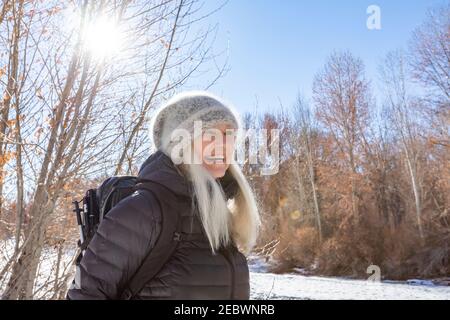 USA, Idaho, Sun Valley, Winterportrait einer lächelnden Frau, die am Fluss entlang wandert Stockfoto