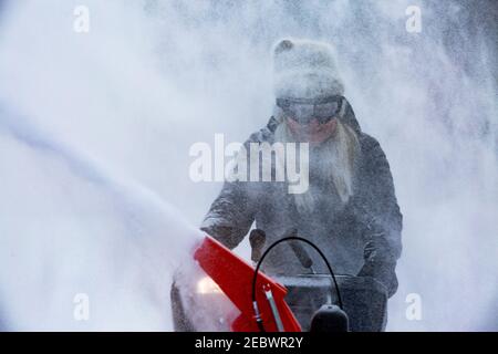 Ältere Frau, die Schnee mit Schneefräsen räumte Stockfoto