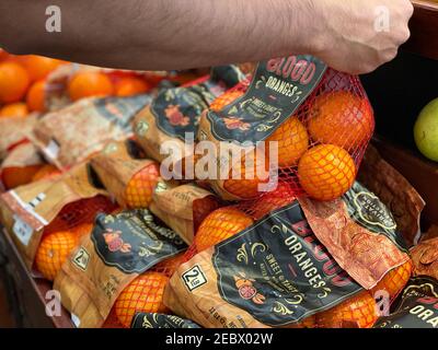 Pico - Robertson, CA USA - Jan 20, 2021: Nahaufnahme der Hand eines Mannes, der einen Beutel mit Blutorangen auf dem Markt aufnimmt Stockfoto