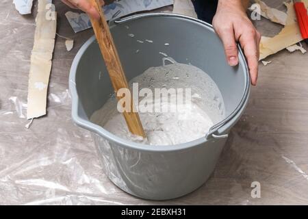 Mischen von weißem Putz in einem Eimer mit einem Rührer. Nahaufnahme. Stockfoto