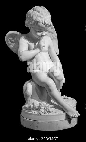 Weiße Engel Figur isoliert auf schwarzem Hintergrund. Amor-Skulptur. Steinstatue des jungen Cherubs Stockfoto