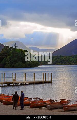 Ruderboote am Ufer von Derwentwater, Keswick. Sonnenstrahlen leuchten in der Ferne Causey Pike und das Newlands Valley. Stockfoto