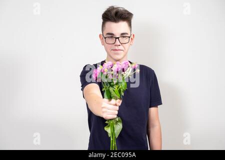 Schüchterner Kerl mit Brille hält einen Strauß verdorrt rosen Stockfoto