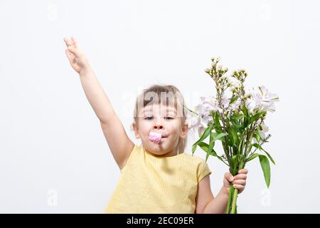 Zeit nach Viel Spaß. Fröhliches Mädchen mit einem Blumenstrauß und einer Pfeife in einem gelben Kleid feiert ihren Geburtstag. Stockfoto