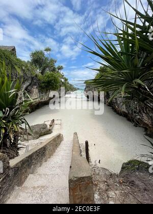 Treppen zwischen Felsen, die zu einem Strand führen. Sansibar. Reise in ein exotisches Land Stockfoto