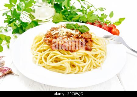 Spaghetti-Pasta mit Bolognese-Sauce aus Hackfleisch, Tomatensaft, Knoblauch, Wein und Gewürze mit Käse und Gabel in einem Teller, Pflanzenöl, würziges Kraut Stockfoto