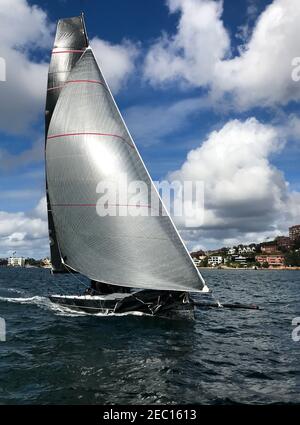 Beeindruckende Yacht-Rennen im Hafen von Sydney. Volles Boot im Blick mit bewölktem dramatischen Himmel und östlichen Vororten dahinter Stockfoto