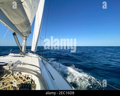 Segelyacht, die an einem ruhigen und sonnigen Tag von den Köpfen des Hafens von Sydney abfährt. Blick vom Cockpit des Bootes über den Horizont, mit ruhigem blauen Meer Stockfoto