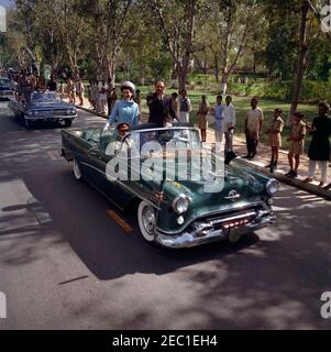 First Lady Jacqueline Kennedyu2019s (JBK) Reise nach Indien und Pakistan: Lahore, Punjab, Pakistan, Autokolonne an Gouverneur von Westpakistan Malik Amir Mohammad Khanu0027s Residenz.. First Lady Jacqueline Kennedy und Präsident von Pakistan, Mohammad Ayub Khan, reisen mit dem Auto zur Residenz des Gouverneurs von Westpakistan, Malik Amir Mohammad Khan, nach Frau Kennedyu2019s Ankunft in Lahore, Punjab, Pakistan. Der Geheimagent James Jeffries sitzt in der Mitte des Vordersitzes des Autos. Stockfoto