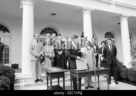 Übergabe der Distinguished Service Medal an General George H. Decker, 12:05pm Uhr. Präsident John F. Kennedy (Mitte, an Mikrofonen) hält Bemerkungen bei der Übergabe der Distinguished Service Medal (DSM) an den scheidenden Stabschef der US-Armee, General George H. Decker (rechts von Präsident Kennedy). Im Hintergrund (L-R): Air Force Aide to the President, Brigadier General Godfrey T. McHugh (mostly hidden on Edge of frame); Chairman of the Joint Chiefs of Staff, General Lyman L. Lemnitzer; Helen Decker; Deputy Secretary of Defense, Roswell L. Gilpatric; Chief of Naval Opera Stockfoto