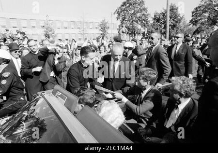 Kongreßfeldzug Reise: Cleveland, Ohio, Ankunft, Rallye, Autokolonne, Abfahrt. Präsident John F. Kennedyu2019s hält während einer Wahlkampfreise vor der St. Edward High School in Lakewood, Ohio; Präsident Kennedy schüttelt die Hände mit dem Rektor, Bruder Charles Krupp. Ebenfalls im Bild: Repräsentant Michael J. Feighan aus Ohio (im Vordersitz des Cabrios, Rücken zur Kamera); Senator Frank Lausche aus Ohio (im Rücksitz mit Präsident Kennedy); Gouverneur von Ohio, Michael V. DiSalle (ganz rechts im Vordergrund); Bruder Florentius Schu (links im Hintergrund stehend Stockfoto