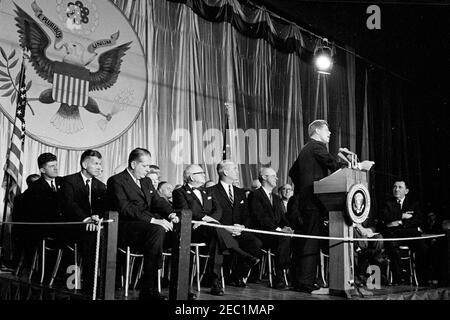 Wahlkampfreise im Kongress: Chicago, Illinois, Ankunft, Autokolonne, Adresse zum Cook County Democratic Dinner, Adresse im Eyrie Crown Theatre. Präsident John F. Kennedy (an einem Rednerpult) hält während einer Wahlkampfreise im Kongress an die Kapitäne des demokratischen Bezirks im Arie Crown Theatre am McCormick Place in Chicago, Illinois, Bemerkungen. Der Geheimagent des Weißen Hauses, Gerald A. u201cJerryu201d Behn, sitzt auf der Bühne links; alle anderen sind nicht identifiziert. Stockfoto